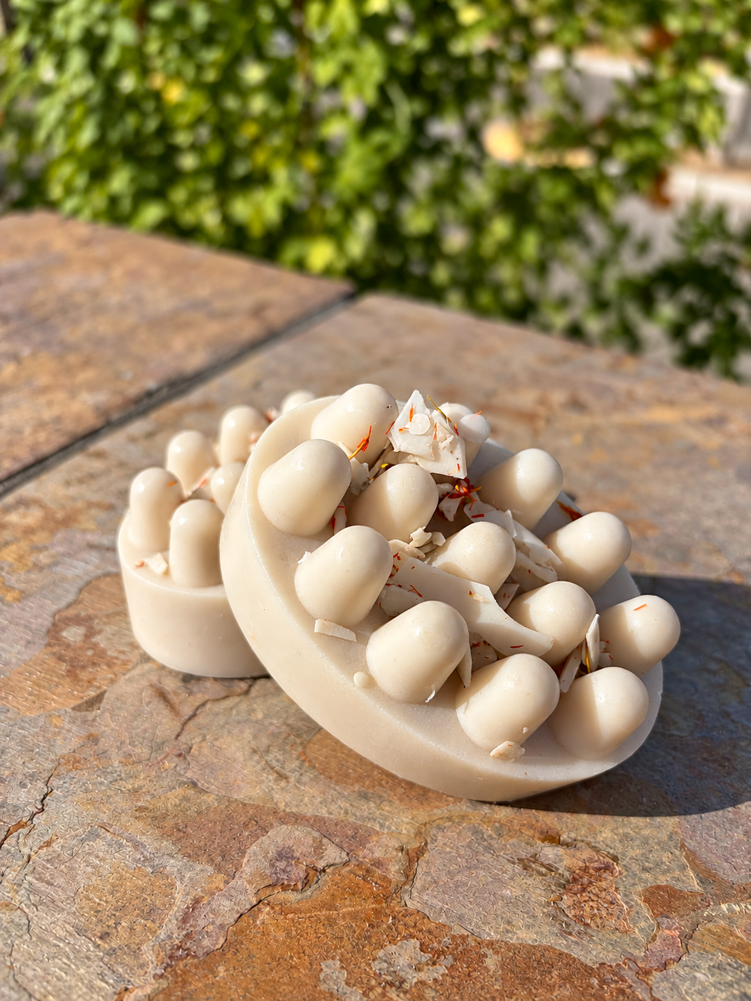 Two cacao goats milk handmade soap bars on a stone ledge